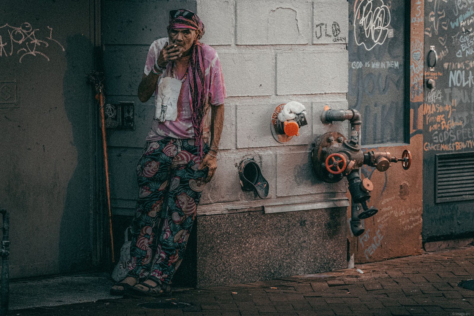 Solitary figure standing in a New Orleans alleyway among graffiti and street textures