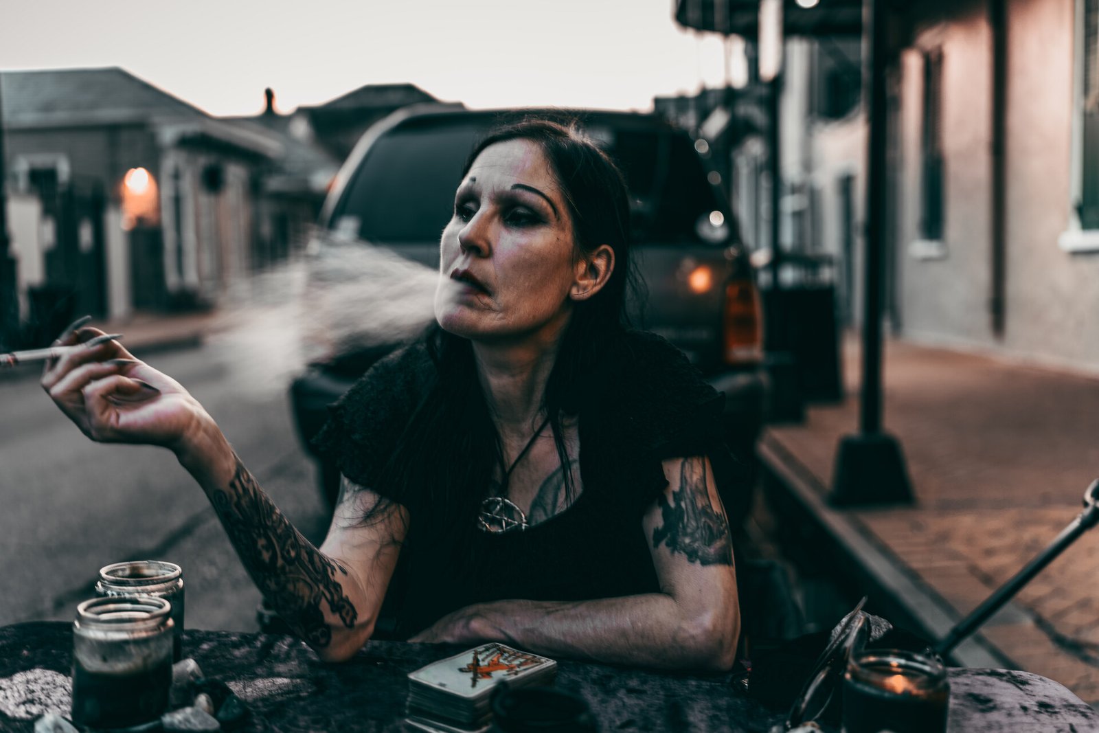 Woman exhaling smoke at a streetside table at dusk, French Quarter, New Orleans, Louisiana
