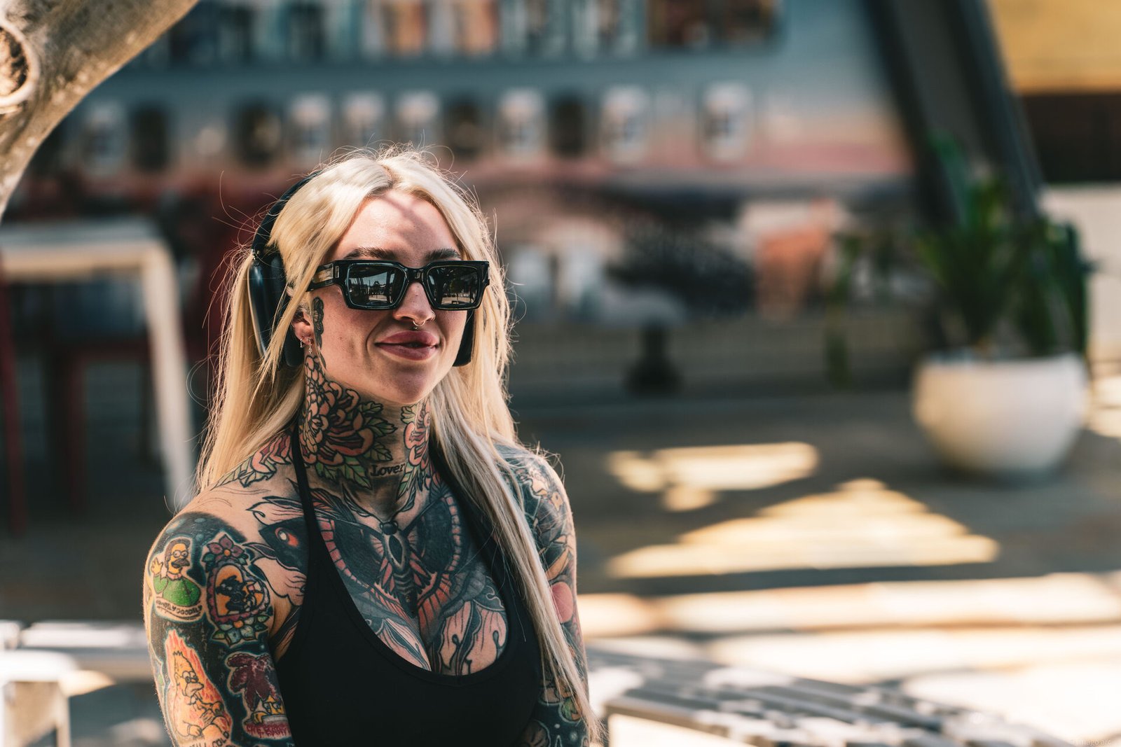 Portrait of a heavily tattooed woman with headphones and sunglasses in warm outdoor light