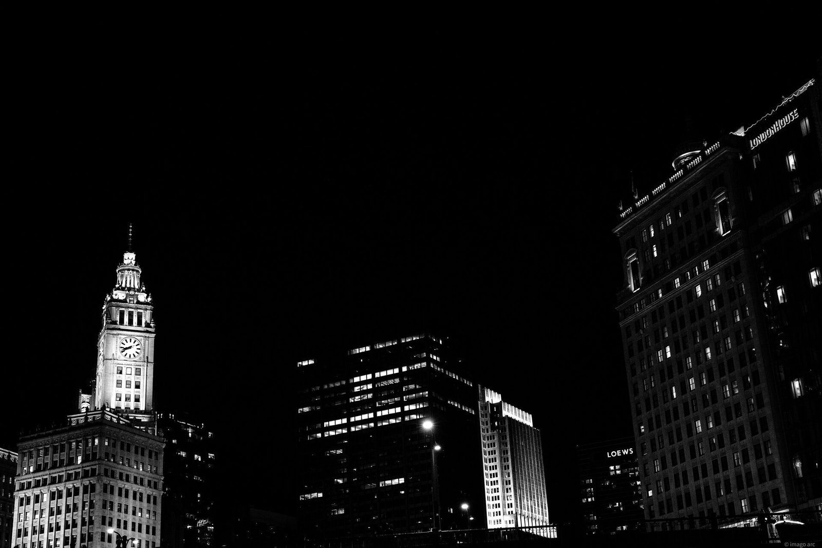 Chicago skyline at night in black and white, Wrigley Building clock tower illuminated against a dark sky