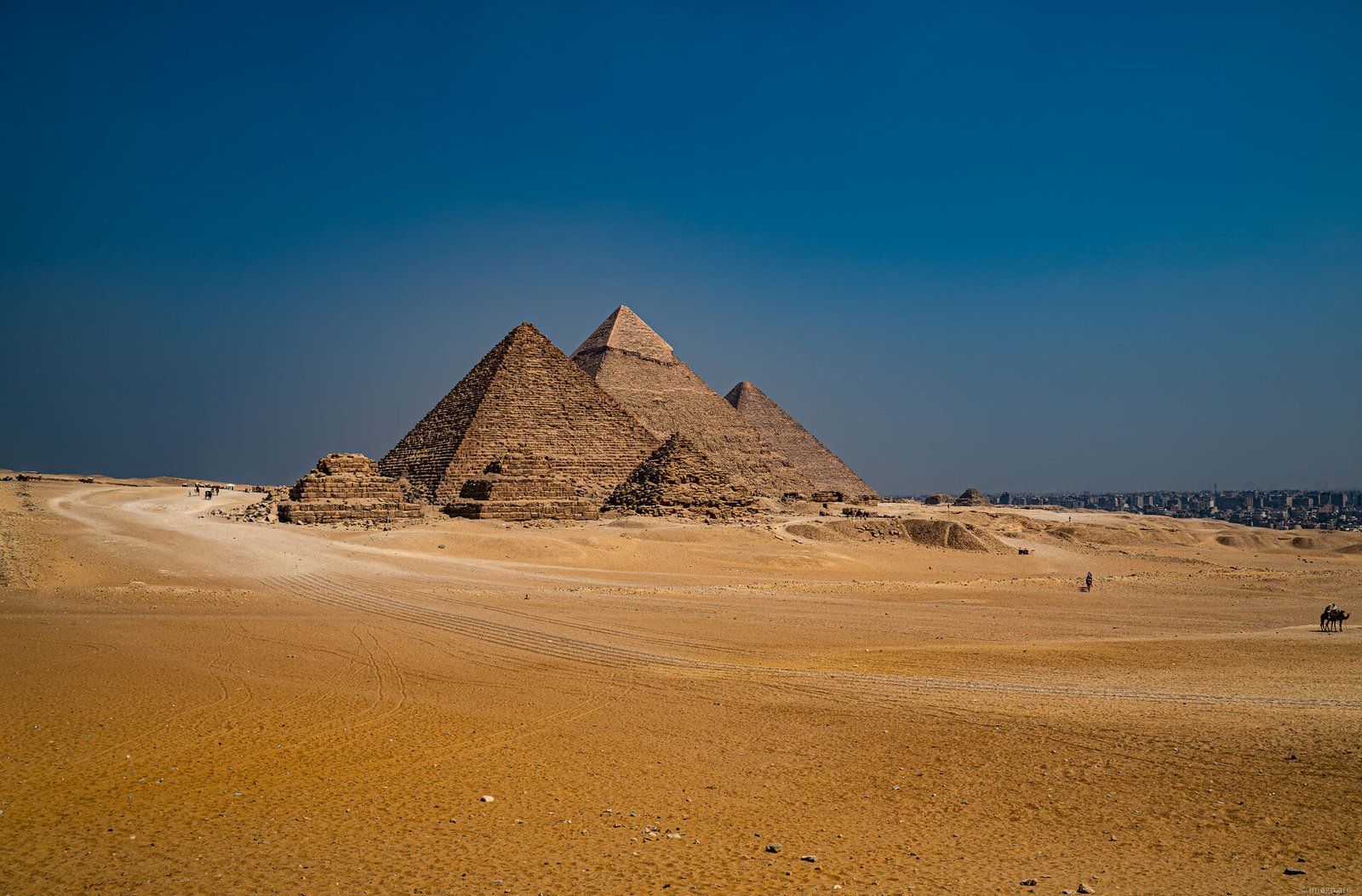 The Great Pyramids of Giza rising from the desert plateau under a deep blue sky, Cairo, Egypt